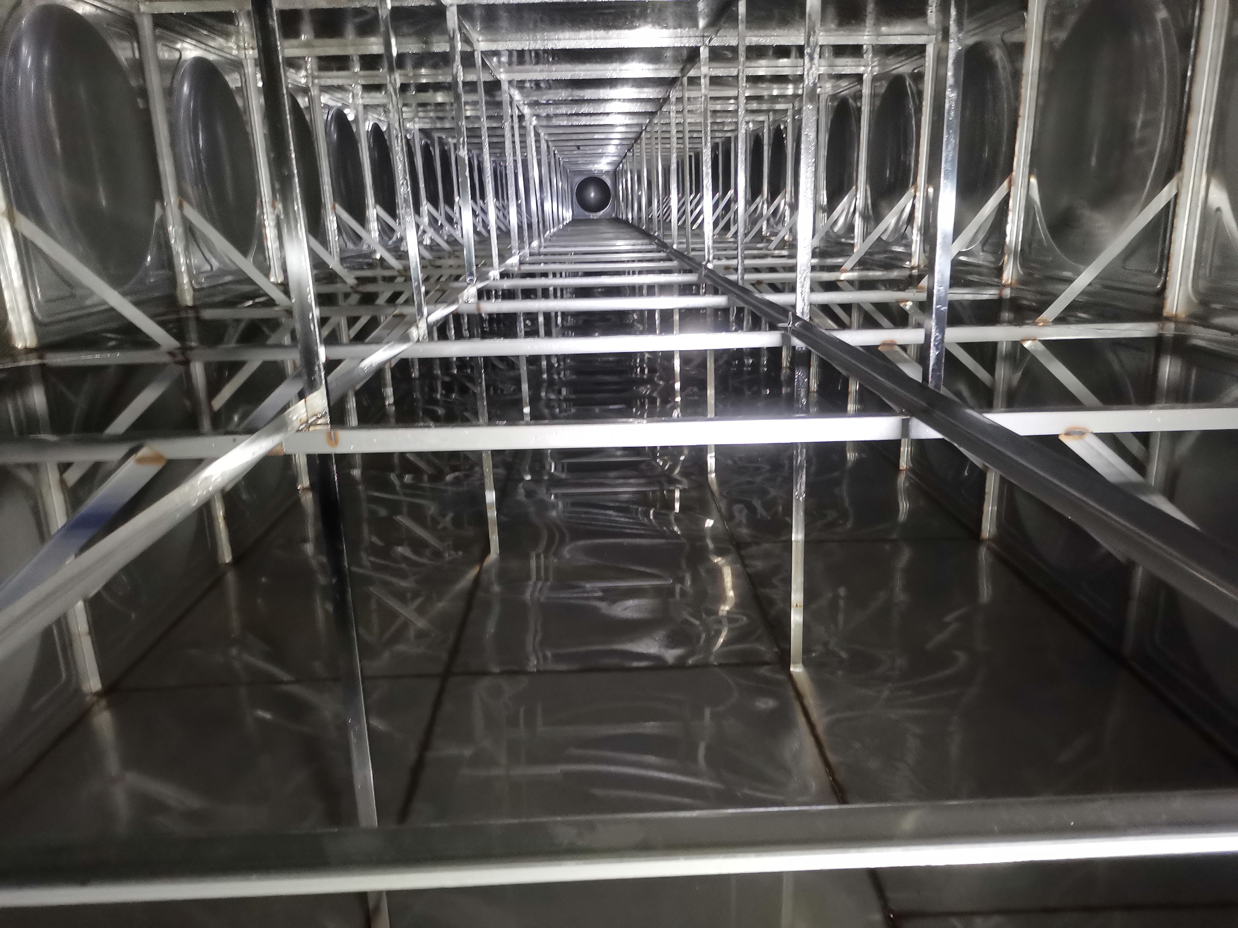 专业水箱清洗作业现场，工作人员穿着防护服进行清洗消毒操作，设备齐全，现场整洁有序